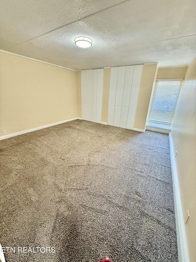 unfurnished bedroom featuring carpet, a textured ceiling, baseboards, and two closets