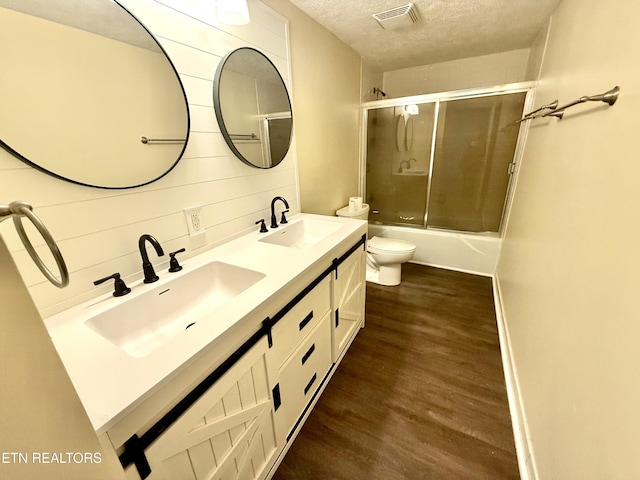 bathroom featuring a textured ceiling, visible vents, a sink, and wood finished floors