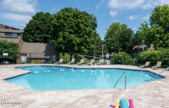 pool with a patio area and fence