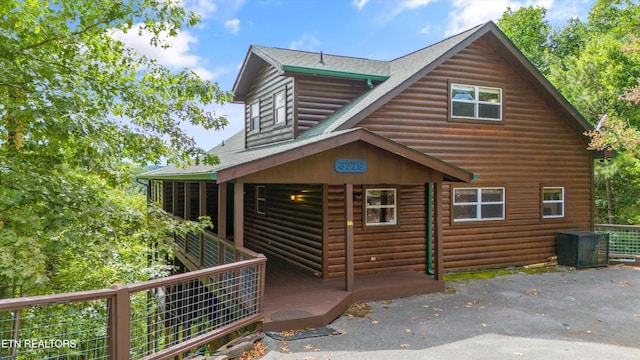 view of front of home featuring a shingled roof and faux log siding