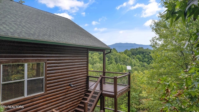exterior space with log veneer siding, roof with shingles, a mountain view, and a forest view