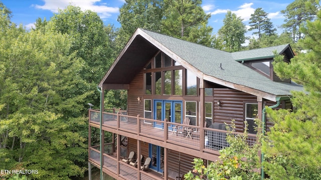 rear view of house featuring faux log siding, roof with shingles, and a wooden deck