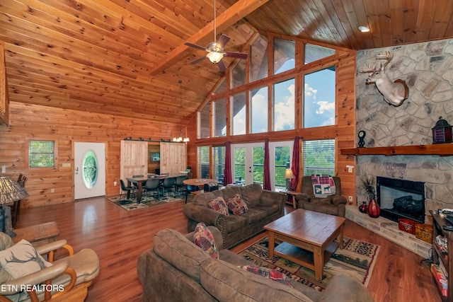 living area featuring a stone fireplace, beamed ceiling, wooden ceiling, and wood finished floors