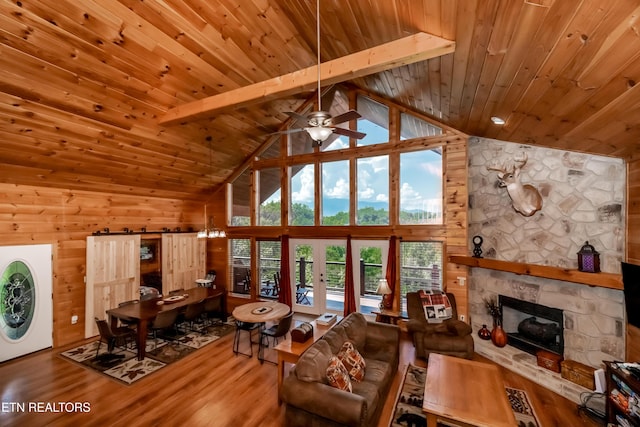 unfurnished living room with high vaulted ceiling, a stone fireplace, wood finished floors, wood ceiling, and beamed ceiling