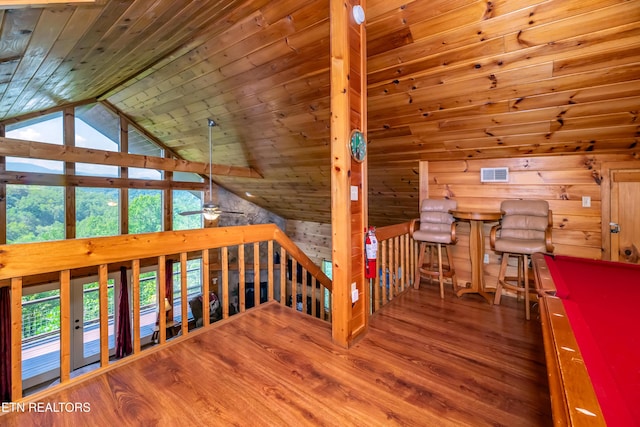 interior space with visible vents, vaulted ceiling, wood walls, wood finished floors, and wooden ceiling