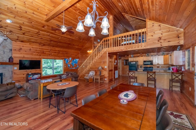 dining room featuring light wood-style floors, wooden ceiling, stairway, and wooden walls