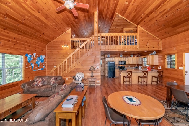 living area with wooden ceiling, wood walls, and stairway