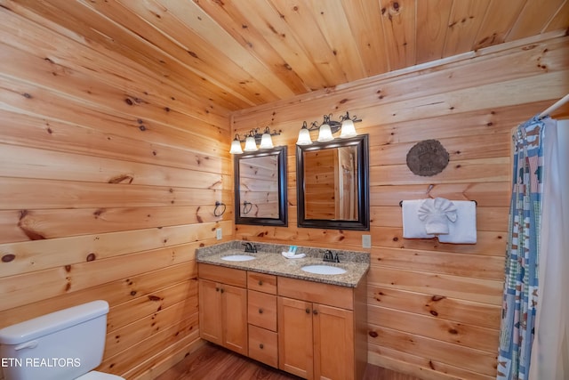 bathroom featuring toilet, wood ceiling, double vanity, and a sink