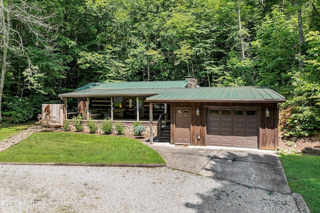 view of front of property with metal roof, an attached garage, concrete driveway, a chimney, and a front yard