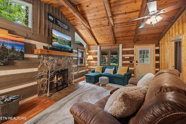 living area featuring beam ceiling, wooden walls, wood finished floors, wooden ceiling, and plenty of natural light