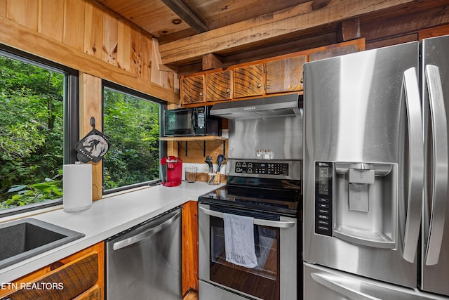 kitchen with light countertops, appliances with stainless steel finishes, a healthy amount of sunlight, and under cabinet range hood