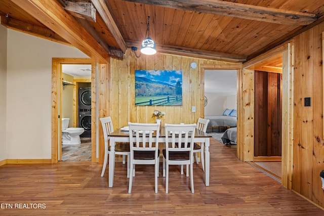 dining area featuring wooden ceiling, wooden walls, stacked washer / dryer, and wood finished floors