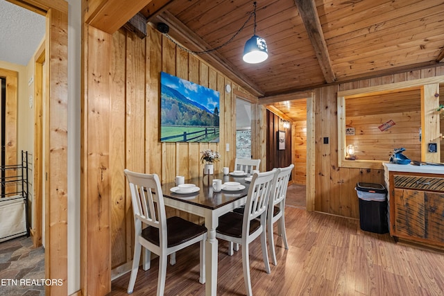 dining room featuring vaulted ceiling with beams, wood walls, wooden ceiling, and wood finished floors