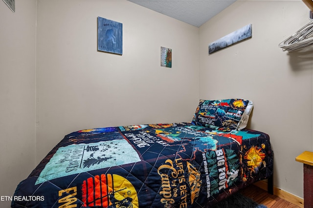 bedroom with baseboards and wood finished floors