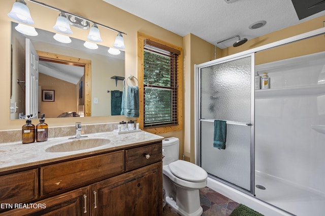 bathroom featuring a stall shower, toilet, a textured ceiling, and vanity