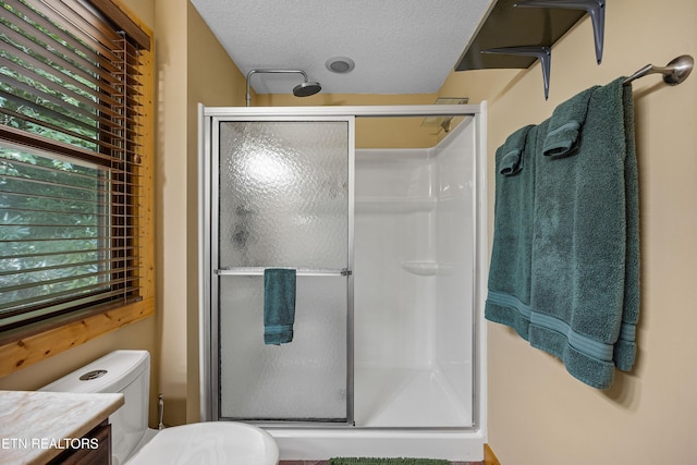 bathroom with a stall shower, a healthy amount of sunlight, a textured ceiling, and toilet