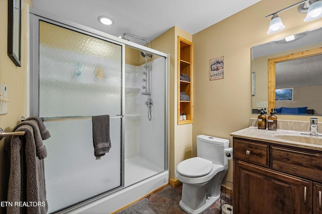 bathroom featuring toilet, a stall shower, a textured ceiling, and vanity