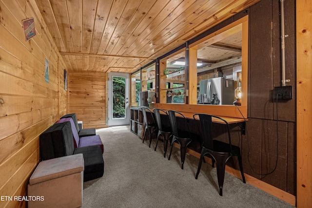 dining area featuring carpet floors, wood ceiling, wood walls, and a dry bar