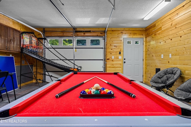 rec room featuring a garage, pool table, a textured ceiling, and wooden walls