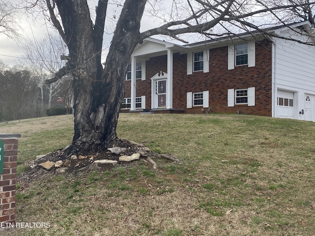 raised ranch with a front lawn, a garage, and brick siding