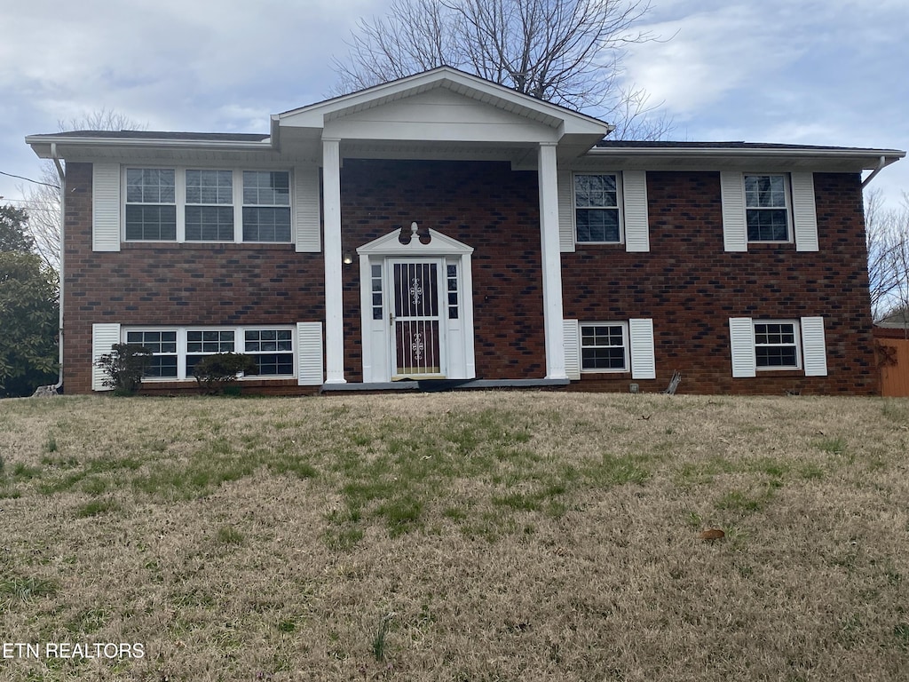 split foyer home with a front lawn and brick siding