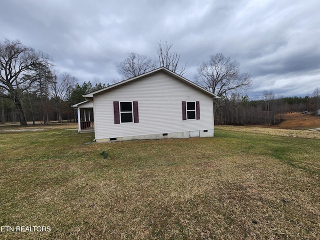 view of side of home with crawl space and a lawn