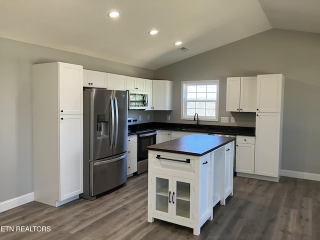 kitchen featuring a kitchen island, a sink, white cabinets, appliances with stainless steel finishes, and dark countertops