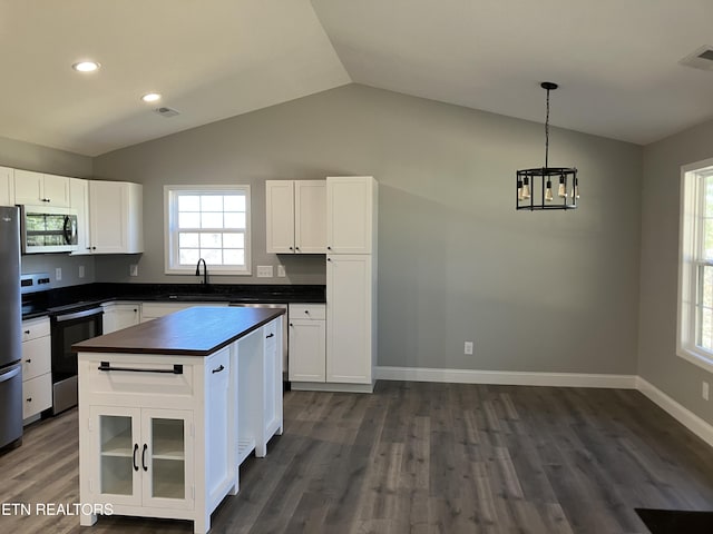 kitchen featuring appliances with stainless steel finishes, vaulted ceiling, white cabinetry, and a sink