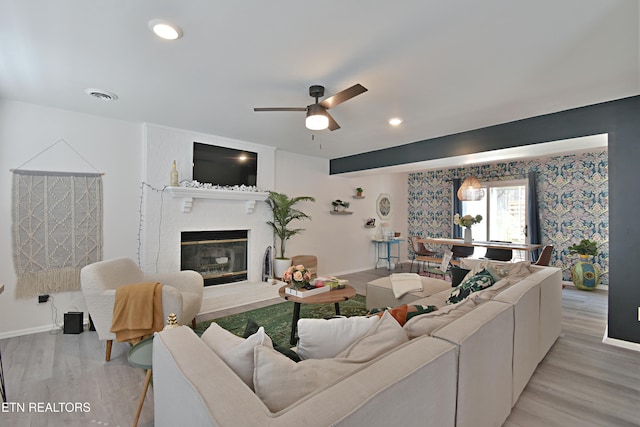 living area with light wood-type flooring, a fireplace, wallpapered walls, and baseboards