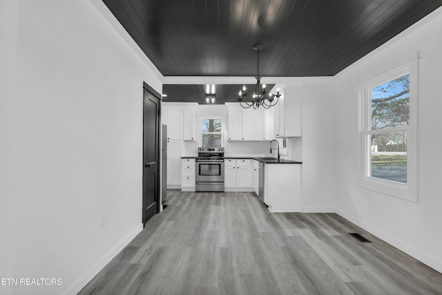 kitchen featuring stainless steel appliances, dark countertops, visible vents, an inviting chandelier, and a sink