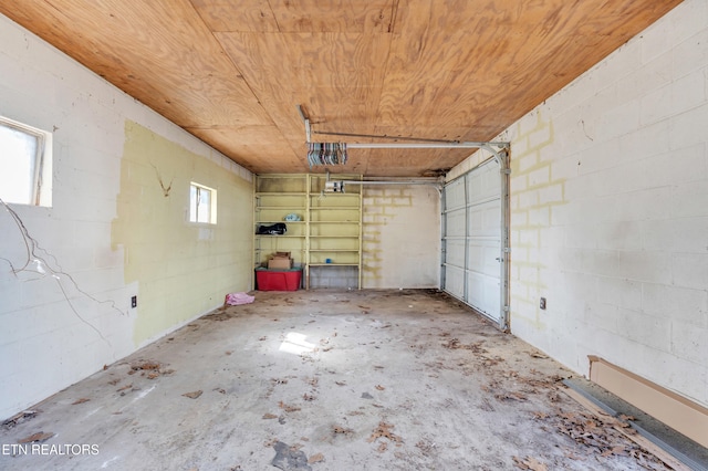 garage featuring concrete block wall, wood ceiling, and a garage door opener