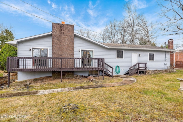 back of house with a deck, a chimney, and a lawn