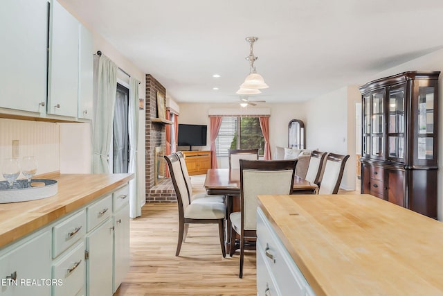 kitchen with a ceiling fan, butcher block counters, open floor plan, decorative light fixtures, and light wood-type flooring