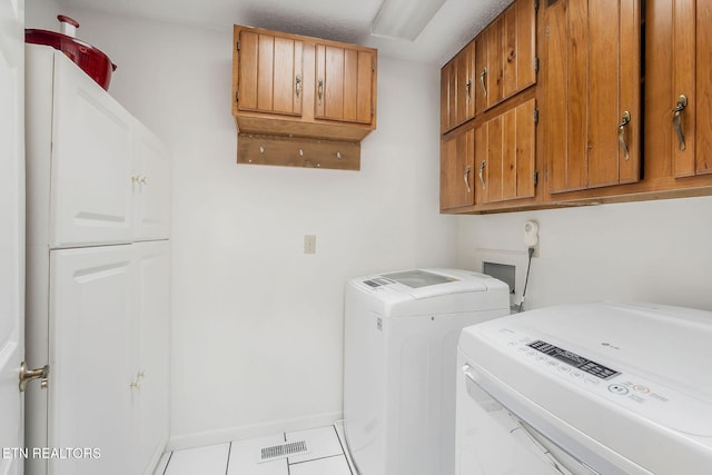 laundry room featuring cabinet space, baseboards, separate washer and dryer, and tile patterned floors