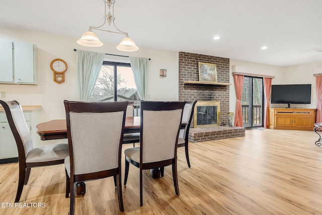 dining room with recessed lighting, a brick fireplace, and light wood-style flooring