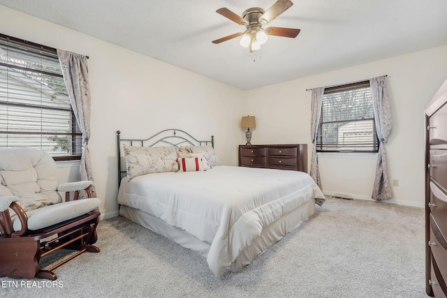 carpeted bedroom with multiple windows, a ceiling fan, and baseboards