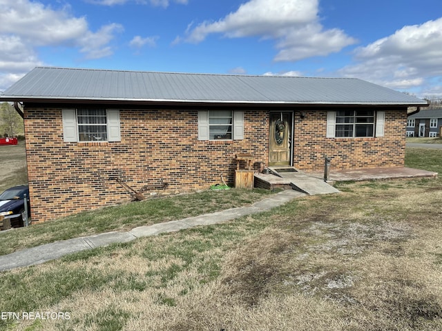 single story home featuring a front yard, brick siding, and metal roof