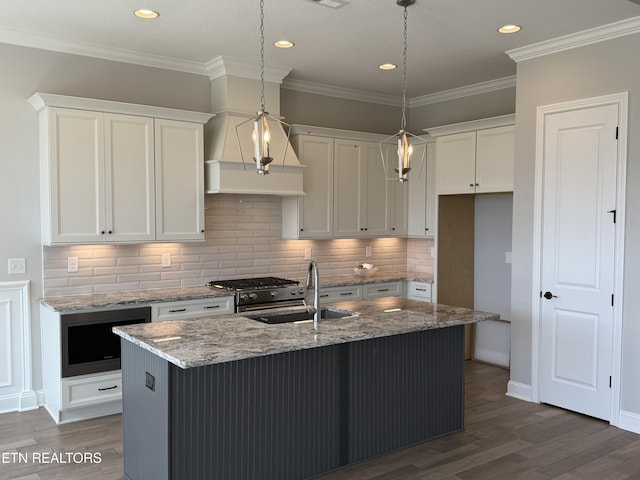 kitchen featuring crown molding, white cabinets, a sink, and wood finished floors