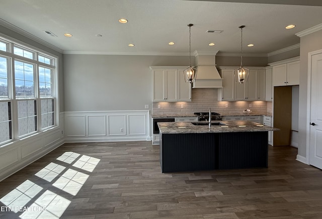 kitchen with tasteful backsplash, visible vents, dark stone countertops, custom exhaust hood, and a sink