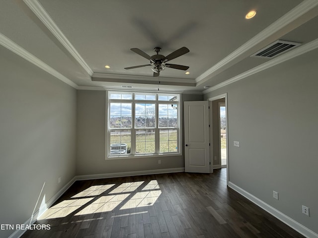 unfurnished room with a tray ceiling, crown molding, visible vents, dark wood-type flooring, and baseboards