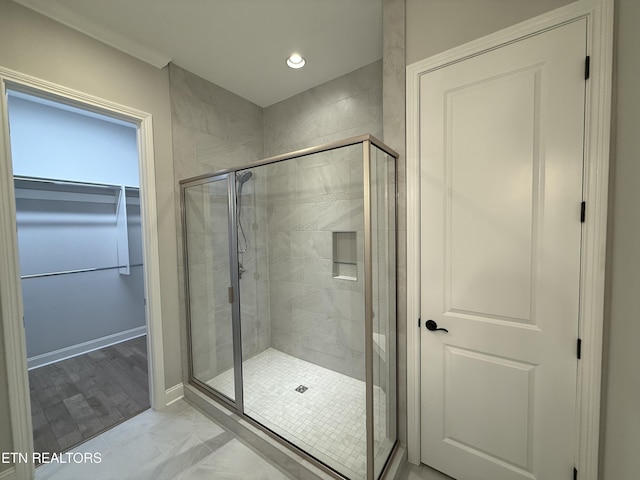 bathroom with marble finish floor, a shower stall, and recessed lighting