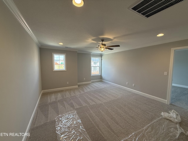 empty room featuring light carpet, ornamental molding, visible vents, and baseboards