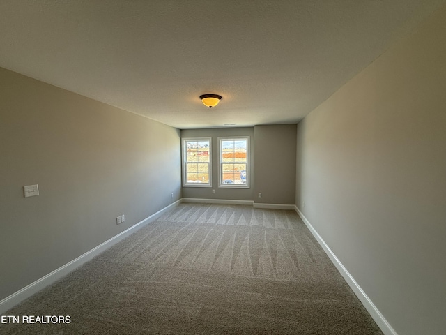 unfurnished room featuring light colored carpet, a textured ceiling, and baseboards