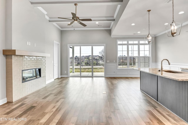 kitchen featuring light stone counters, wood finished floors, ornamental molding, a sink, and open floor plan
