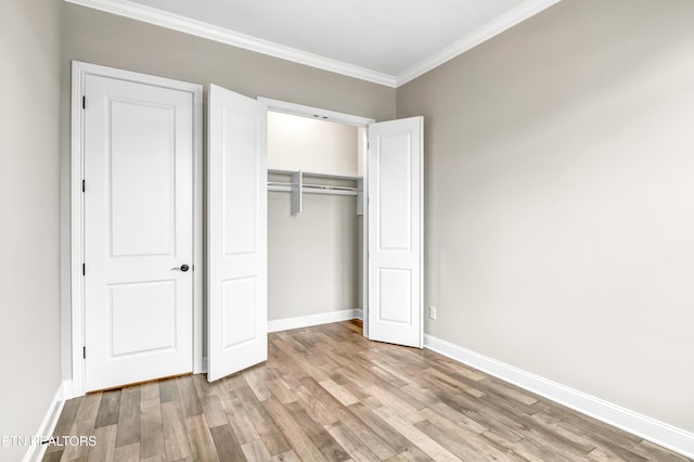 unfurnished bedroom featuring wood finished floors, baseboards, a closet, and ornamental molding