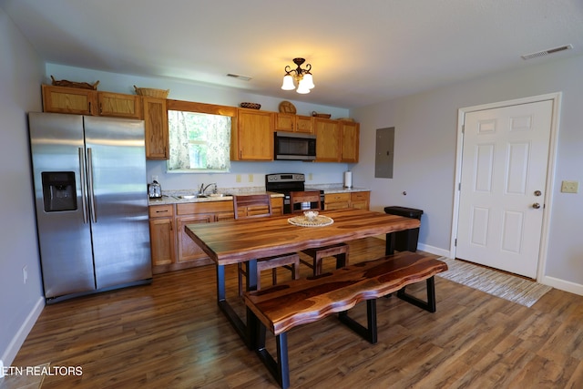 kitchen with appliances with stainless steel finishes, a sink, dark wood-style floors, and baseboards