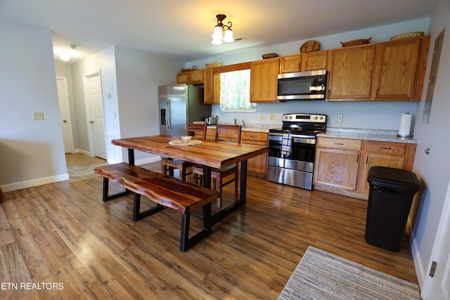 kitchen featuring appliances with stainless steel finishes, dark wood-style floors, light countertops, and baseboards