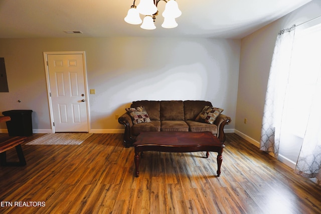living area featuring a chandelier, baseboards, wood finished floors, and electric panel