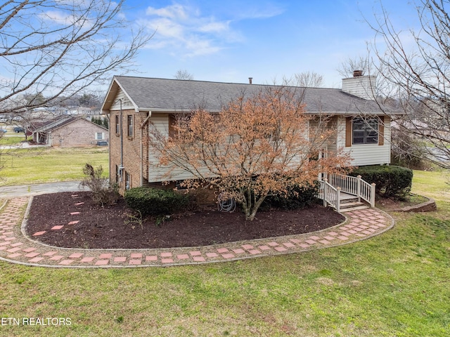 view of side of property with a yard, brick siding, roof with shingles, and a chimney