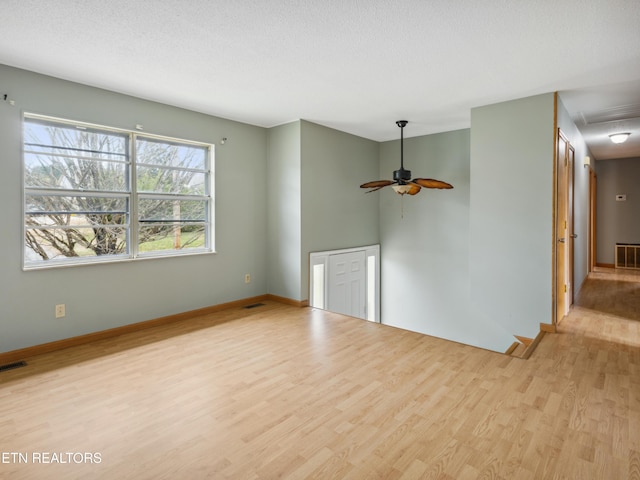 unfurnished living room featuring light wood-style flooring, a ceiling fan, baseboards, and a textured ceiling